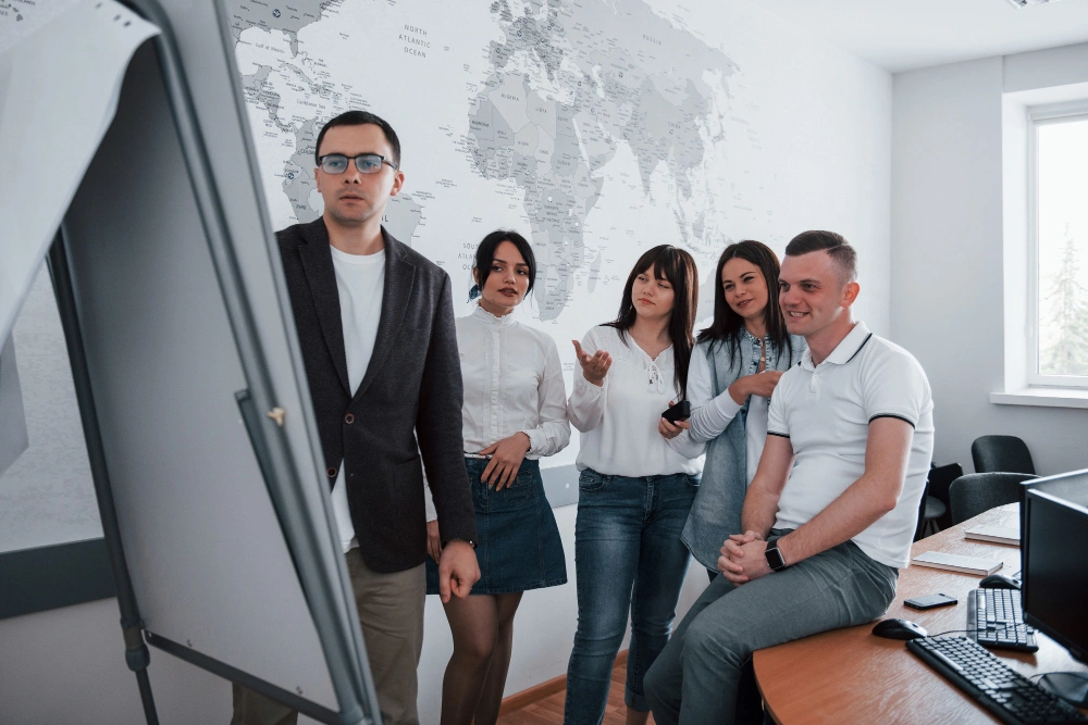 Team discussing strategy around a whiteboard in a modern office, collaborating on Growth Navigate Funding planning and ideas